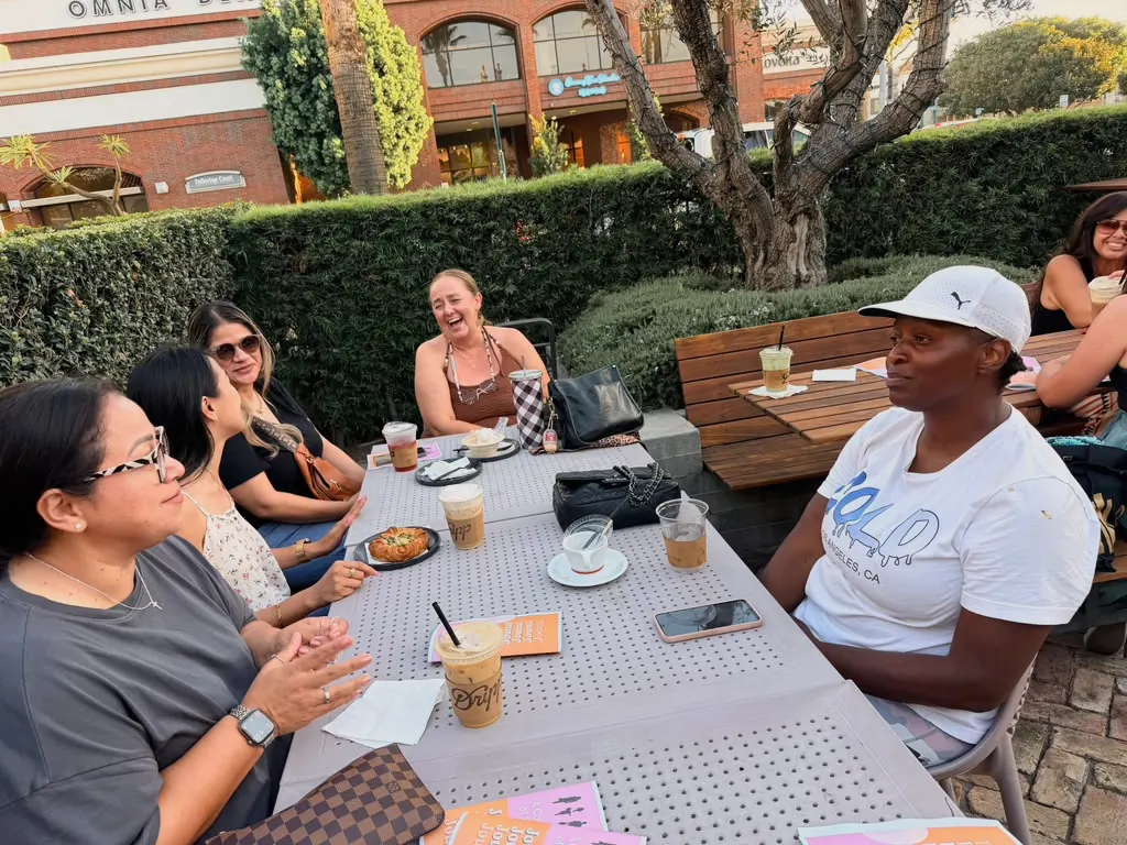 Women sharing iced coffee and conversation around an outdoor café table